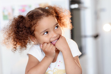 Head shot portrait healthy attractive mixed race little girl with curly ringlets hairstyle and pretty face posing indoor looking at camera. Natural beauty innocence and new generation concept/