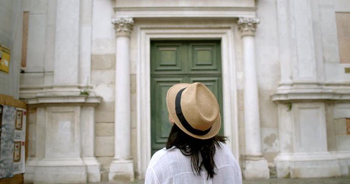 Woman Traveller In Front Of Massive Antique Door From Behind In Fedora In Historic Venice Italy