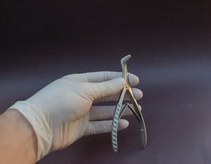 especulo nasal para examen médico de acero inoxidable sostenido por mano con guante blanco