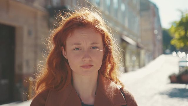 Sick miserable young beautiful red-haired girl coughing into fist feeling bad unhealthy suffering symptoms of coronavirus. Outdoor portrait. Pandemic. Healthcare.