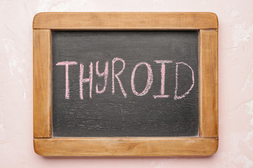 Board with text THYROID on color background