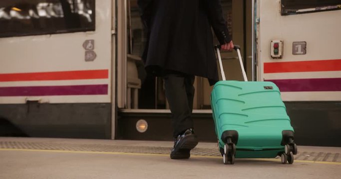 Close up of businessman boarding train with trolley luggage
