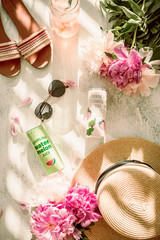 Summer flatlay. Sunglasses, summer hat, flip flops, peony flowers and refreshing sparkling water in cans. Bright and colorful. Direct sunlight. Harsh sunlight. Flat lay on white background.Summer time