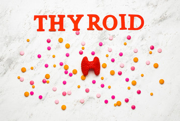 Word THYROID with pills on white background