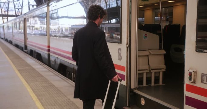 Businessman boarding train on station with trolley luggage