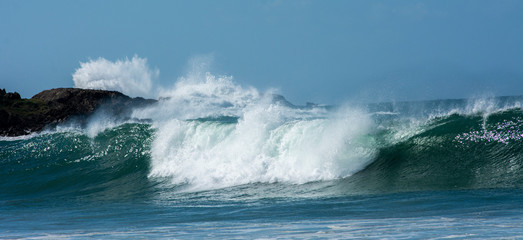 waves breaking over rocks, large swell, crystal clear water, green-blue