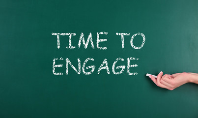 Woman pointing at chalkboard with text Time To Engage, closeup