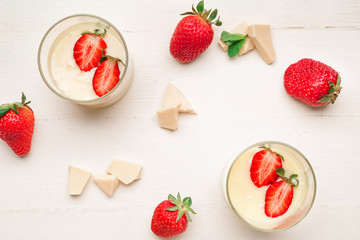 Glasses with tasty strawberry and melted chocolate on white table