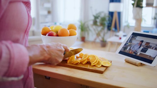 Senior woman preparing food in kitchen indoors, following food vlogger.