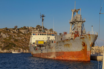 On the pier stands an iron old marine ship covered in rust