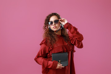 Beautiful young African-American woman with stylish bag on color background