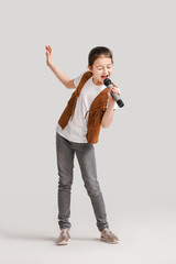 Cute little girl singing against light background