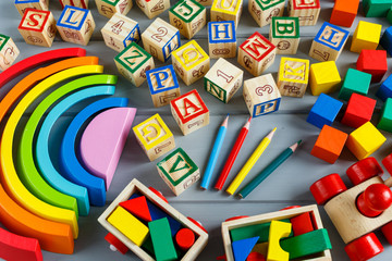 Multicolored wooden cubes with letters on gray background. Set for studying alphabet. Education, back to school concept. Top view, copy space