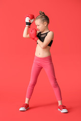 Little girl in boxing gloves on color background