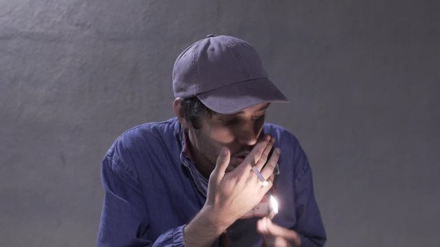 Artist boy man lights cigarette using match smokes outside