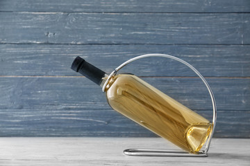 Holder with bottle of wine on wooden background