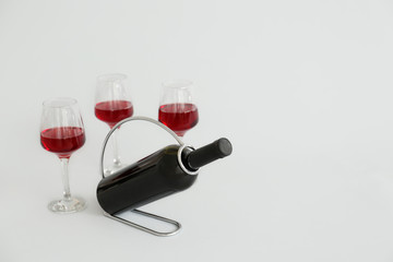 Holder with bottle and glasses of wine on grey background