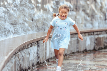 Happy beautiful girl running through the spray of water. © lialia699