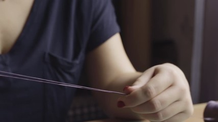 Close-up of a woman's hands working with string in her craft workshop, creating leather bindings for a DIY journal. - Powered by Adobe