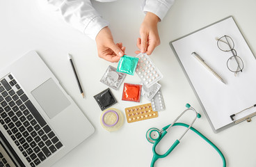 Female gynecologist with different contraceptives in clinic, top view