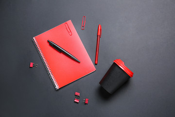 Takeaway cup for drink and stationery on dark background