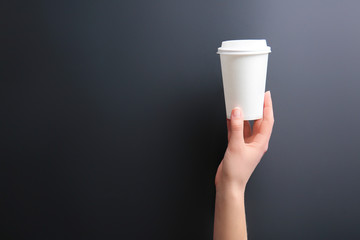 Hand with takeaway cup for drink on dark background