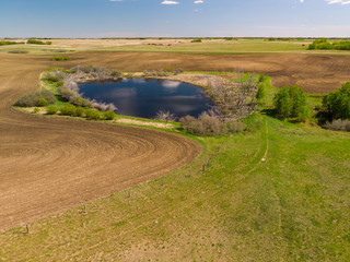an aerial view of a secluded, calm and peaceful pond in the prairie province of Saskatchewan, Canada