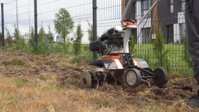 Worker man plow townhouse yard with cultivator. Preparing for lawn sow. Gimbal