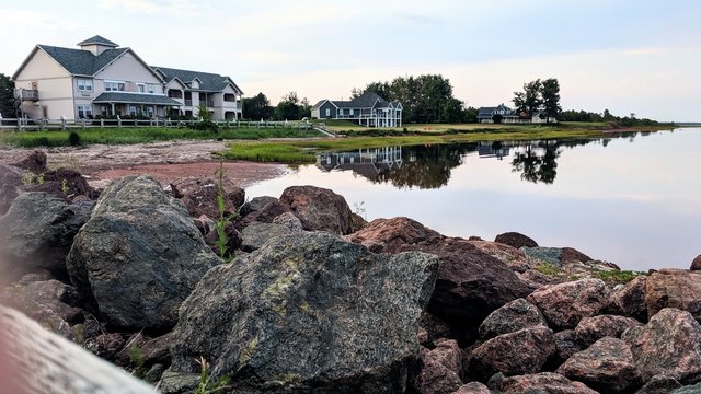 A calm summer evening in Northport pier, an area south of Alberton, PEI, creates still Atlantic Ocean waters that reflect a beautiful image of east coast waterfront cottages.