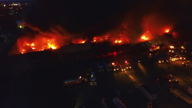 Firetrucks outside a flaming building, during night time, in Los Angeles, California, USA - Aerial tracking drone shot