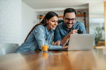 Cheerful couple looking pictures on laptop computer, copy space, portrait.