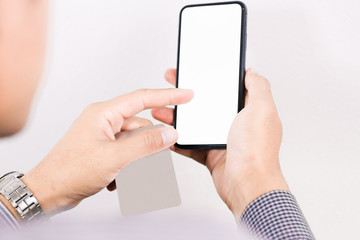 The hands of an Asian man holding a credit card and using phone payments to make online purchases with a credit card in a phone application or home stay website and buying products online.