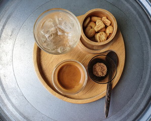 Hot espresso coffee with soft foam, served in a clear coffee cup, sugar, biscuits and cold water. For the benefit of the body, do not drink more than 2 cups (10 ounces) view from the top of the table.