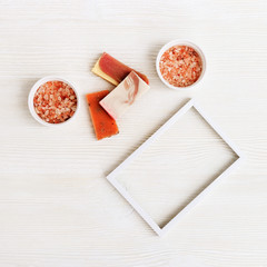 Bright handmade soap bars and sea salt with white metal frame. Flat lay composition with cosmetic products for bathroom, spa, beauty cosmetic and body care treatment with copy space for your text.