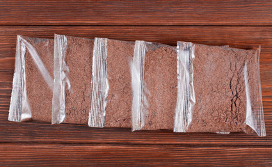 Flax porridge in a transparent plastic bags on a wooden background. Top view.