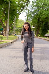 Full body shot of young beautiful Indian woman in the streets at the park