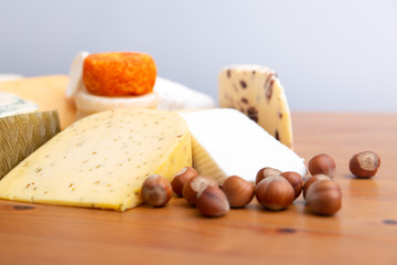 Spicy cheese slices and macadamia nuts on wooden table. Closeup shot. Delicatessen or restaurant cuisine concept