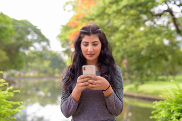 Young beautiful Indian woman using phone at the park outdoors