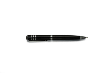 One black ballpoint pen lying on a white background in the middle of the photo