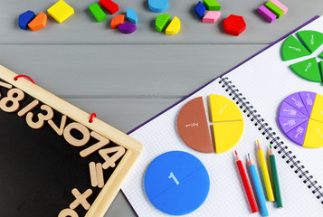 Close up of Multicolored math fractions, pencils on the open notepad on gray wooden table....
