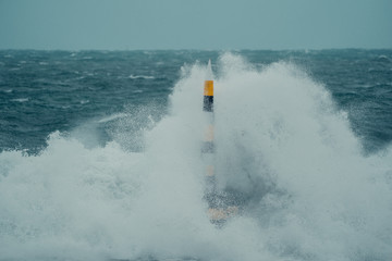 A once in a decade storm hitting the iconic Cottesloe bollard. Huge waves crash against the bollard with heavy rain pouring down. 