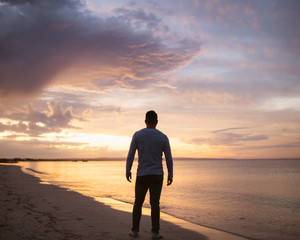 A lone man staring into the distance at an epic sunset over the Busselton beach. 