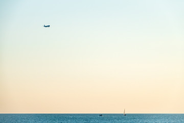 Airplane flying over sea water on sunset sky background. Ttravel aircraft silhouette