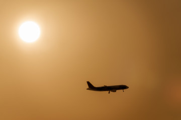 Airplane landing against setting sun. Travel concept.