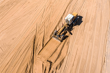 top view of industrial road grader on construction site. leveling the ground for construction of...