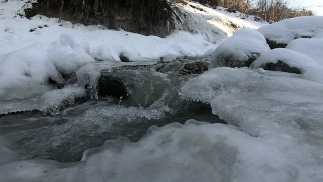 Water flowing through a little frozen river in the forest of the Alps in Austria.