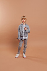 girl in daily clothes (jeans, jacket, sneakers) on a beige background