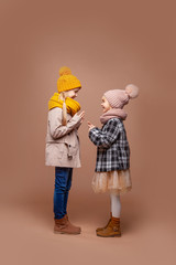 Two girls dressed in autumn street clothes talking, laughing and gesturing