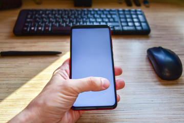 close up male hand holding news mobile device on desktop background