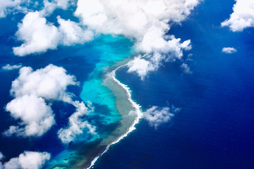 aerial view of sea and coral reefs amidst clouds and sky © JX